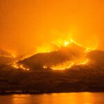 Wildfire burning across hillside terrain